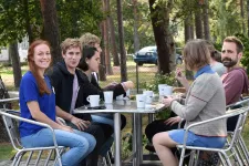 Participants sitting at a table outside, drinking coffee. Photo.