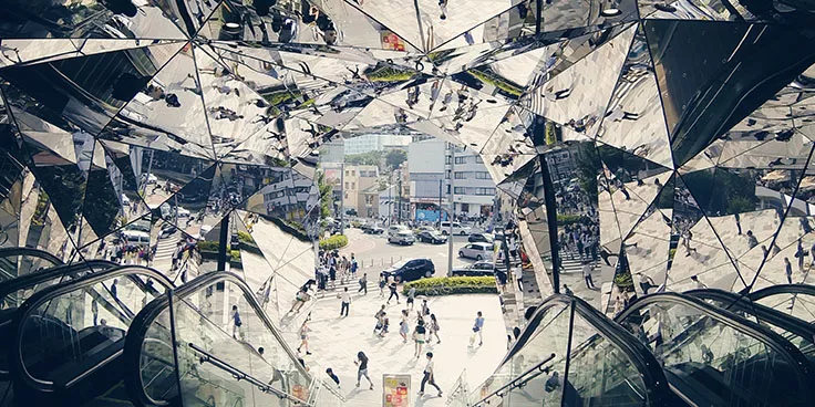 An escalator going down with mirrors on the walls and the ceiling. Photo.