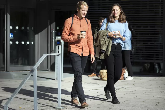 Två studenter går ut från byggnad. Foto. 